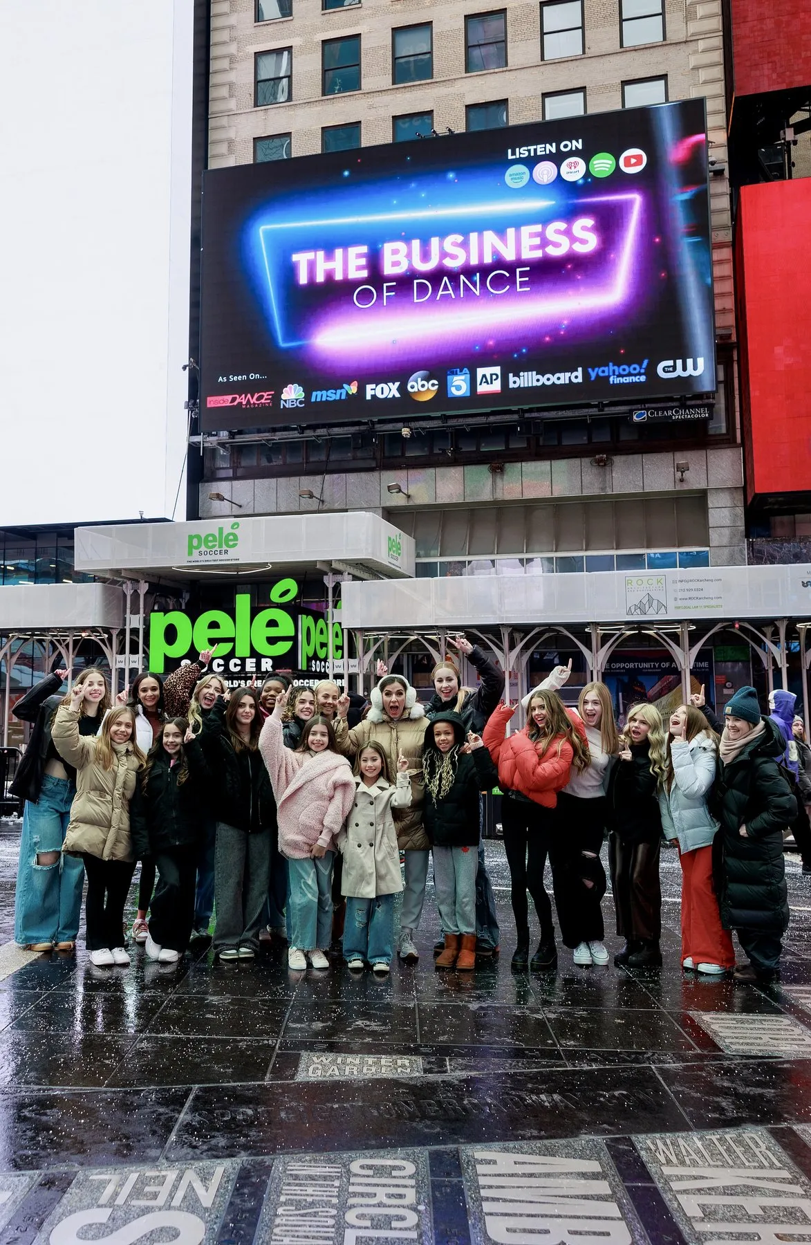 Menina Fortunato’s podcast on a Times Square billboard, with her dancers below it, February 2025.