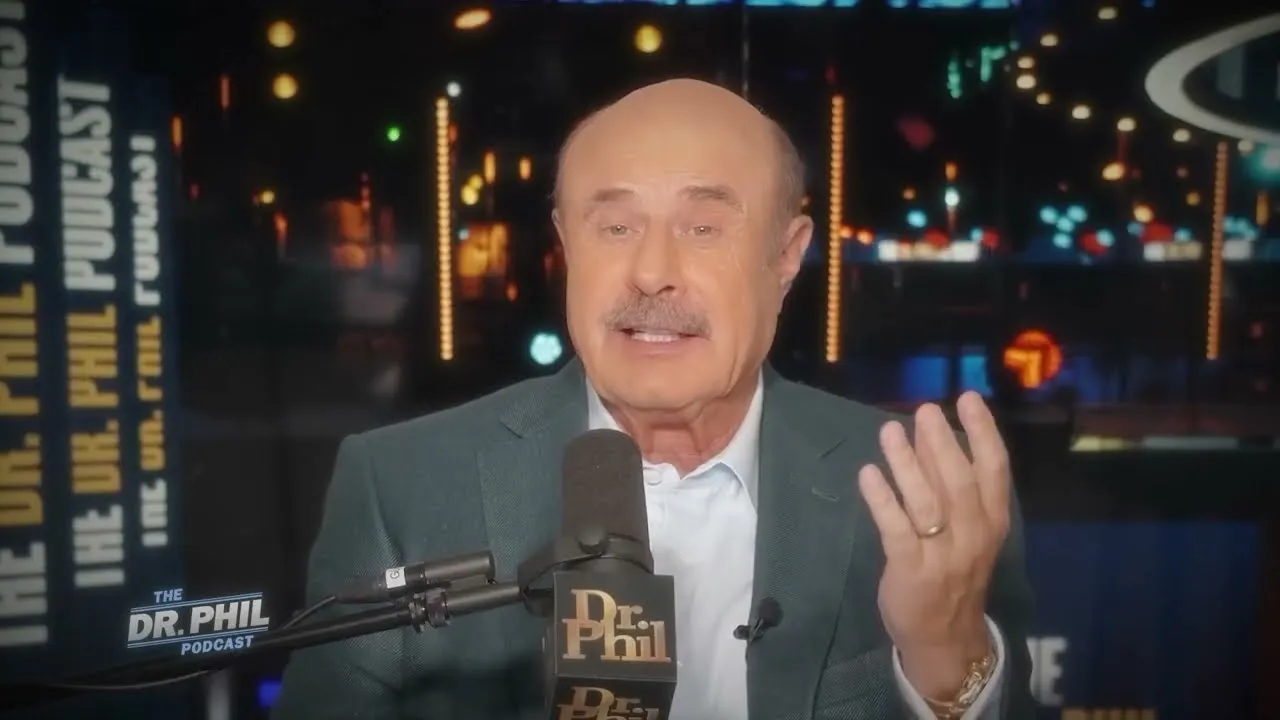 Dr. Phil speaking at the microphone on The Dr. Phil Podcast set